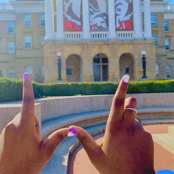 Student hold up W hands in front of Bascom Hall
