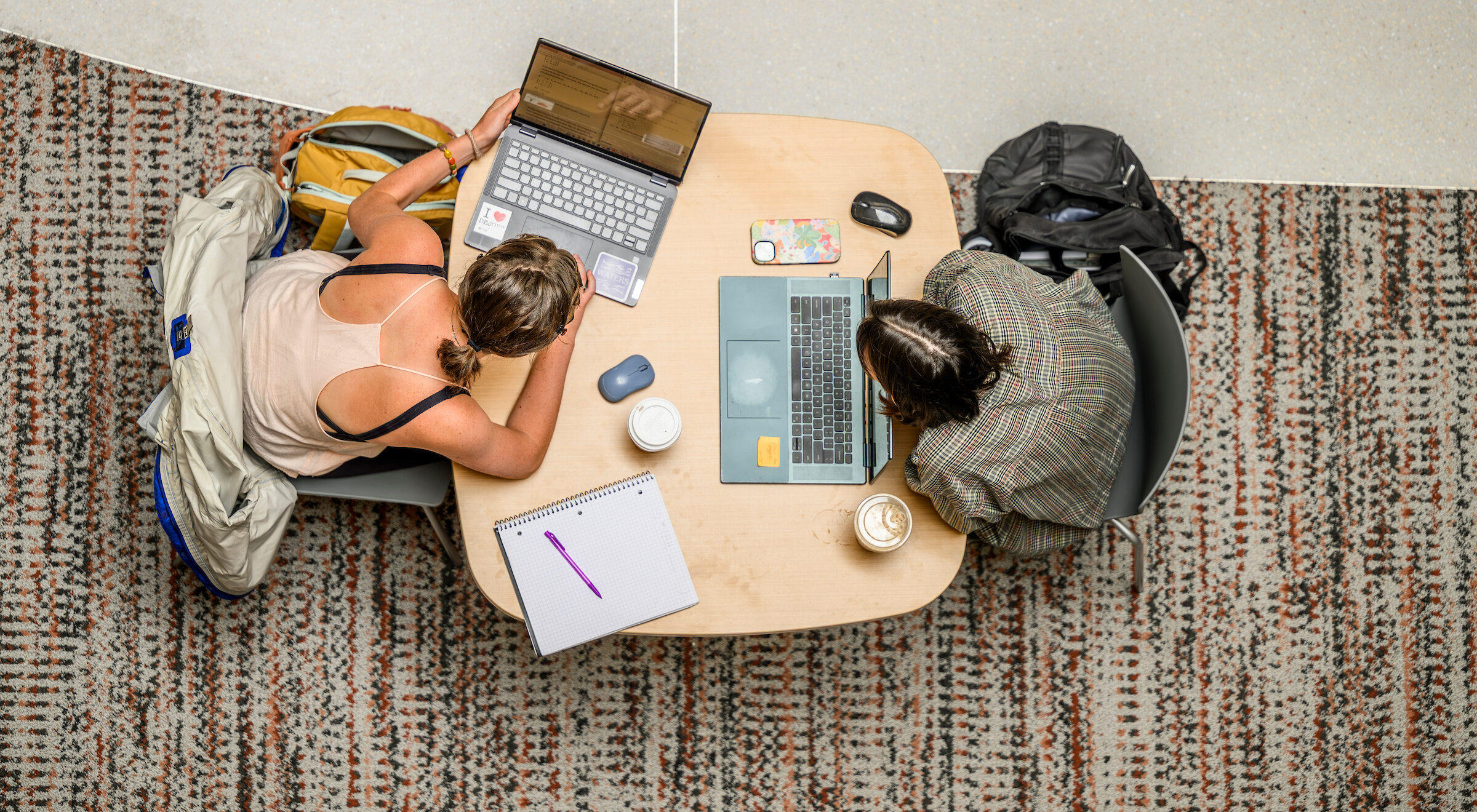 Students study on their laptops between classes at Morgridge Hall as seen from above