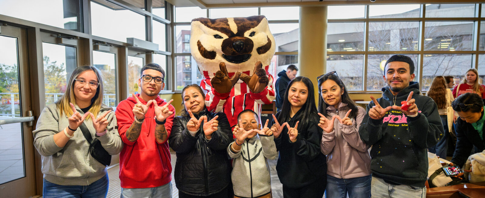 a student poses for a photo with Bucky and her family who are visiting from Chicago during Family Weekend