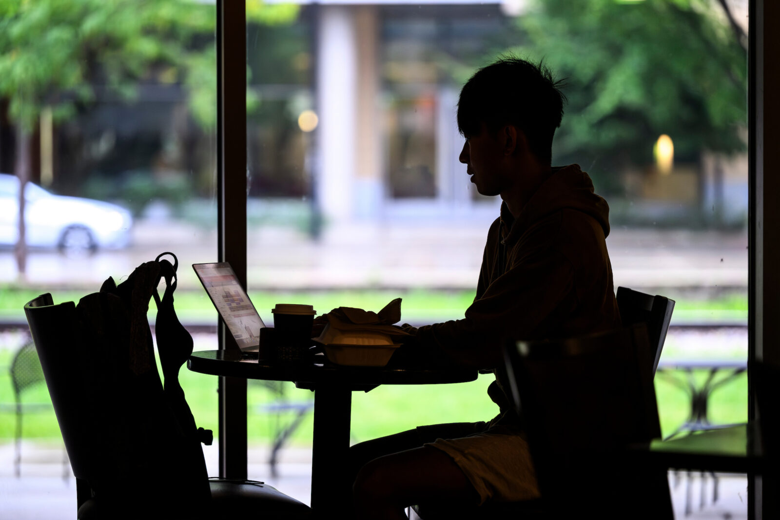 A silhouette of a student studying in front of a window