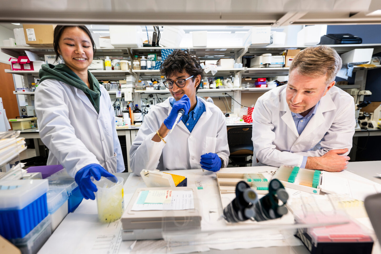 A professor and two students work on scientific research in a lab