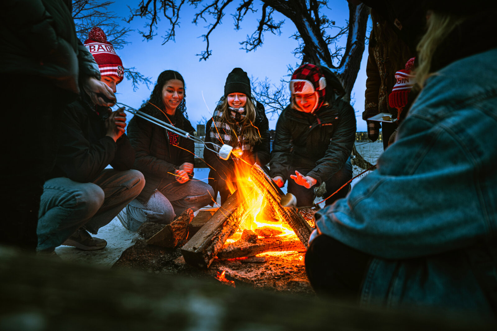 Students roast marshmallows and warm themselves around a campfire in a fire circle at Picnic Point after a winter snowfall